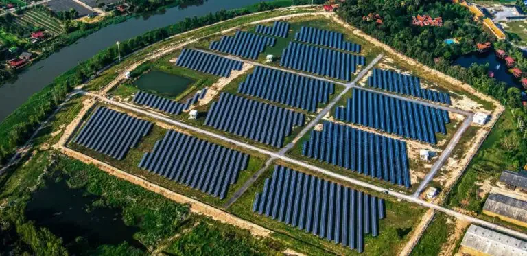 Aerial view of a completed utility-scale ground mount solar farm showing array blocks and internal access roads