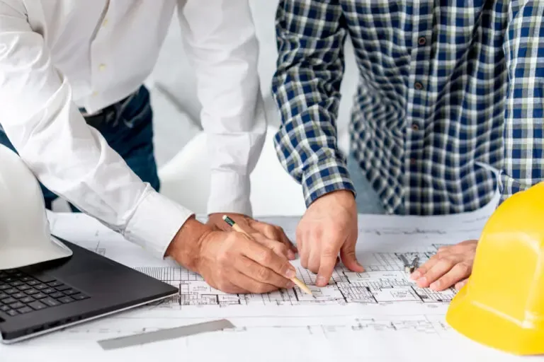 Project engineers reviewing solar plant drawings together on site during a construction coordination meeting