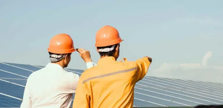 Site engineers in safety gear inspecting installed solar modules