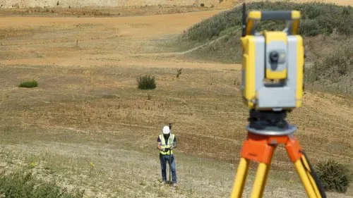 Surveyor operating a total station on sloping open land during a solar site survey